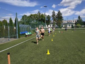 Grafika przedstawia wakacyjny turniej na Orliku - bieganie